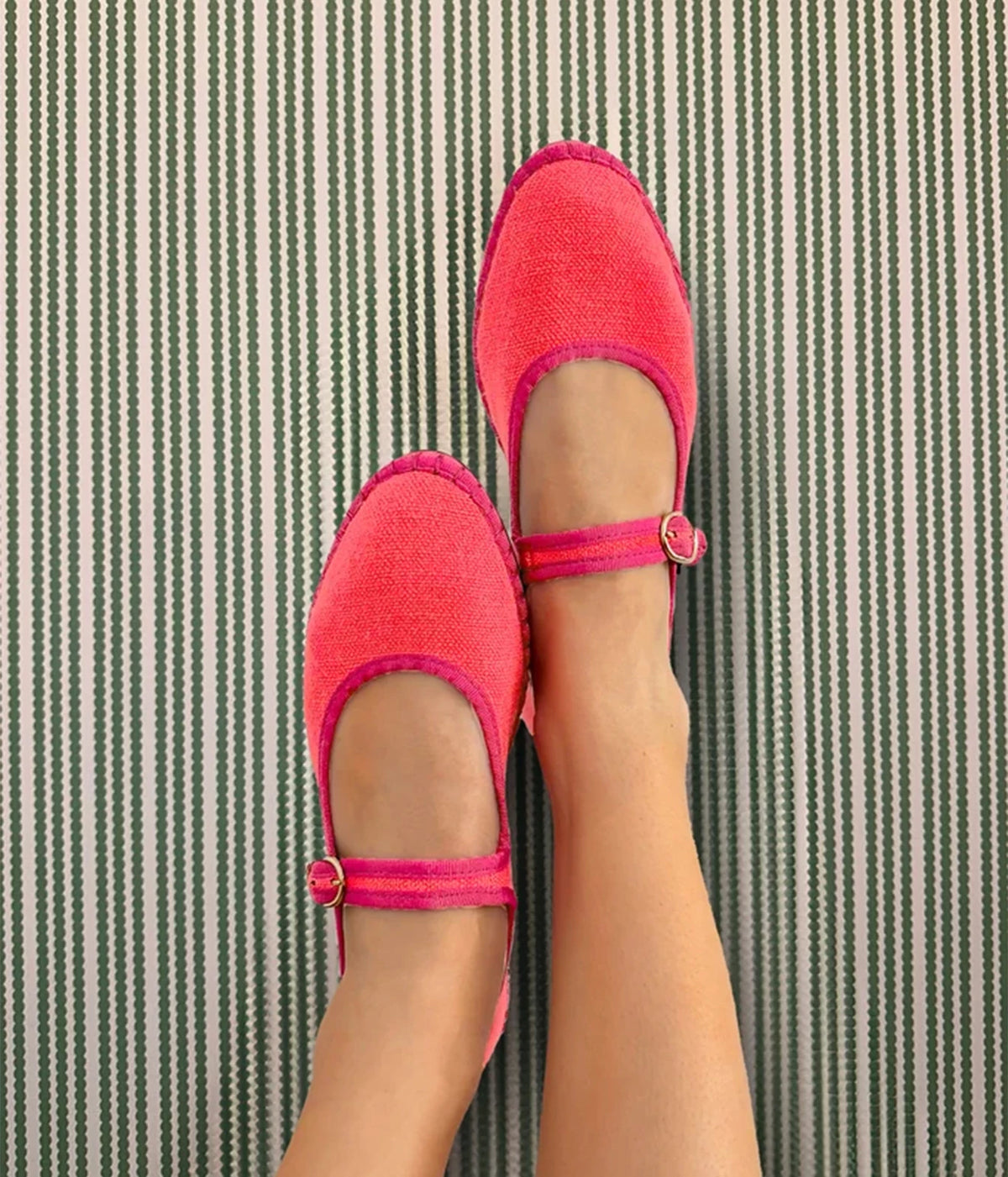Overhead view of raised legs wearing the Flabelus Lago in Geranio, showing the linen uppers and pink buckle straps