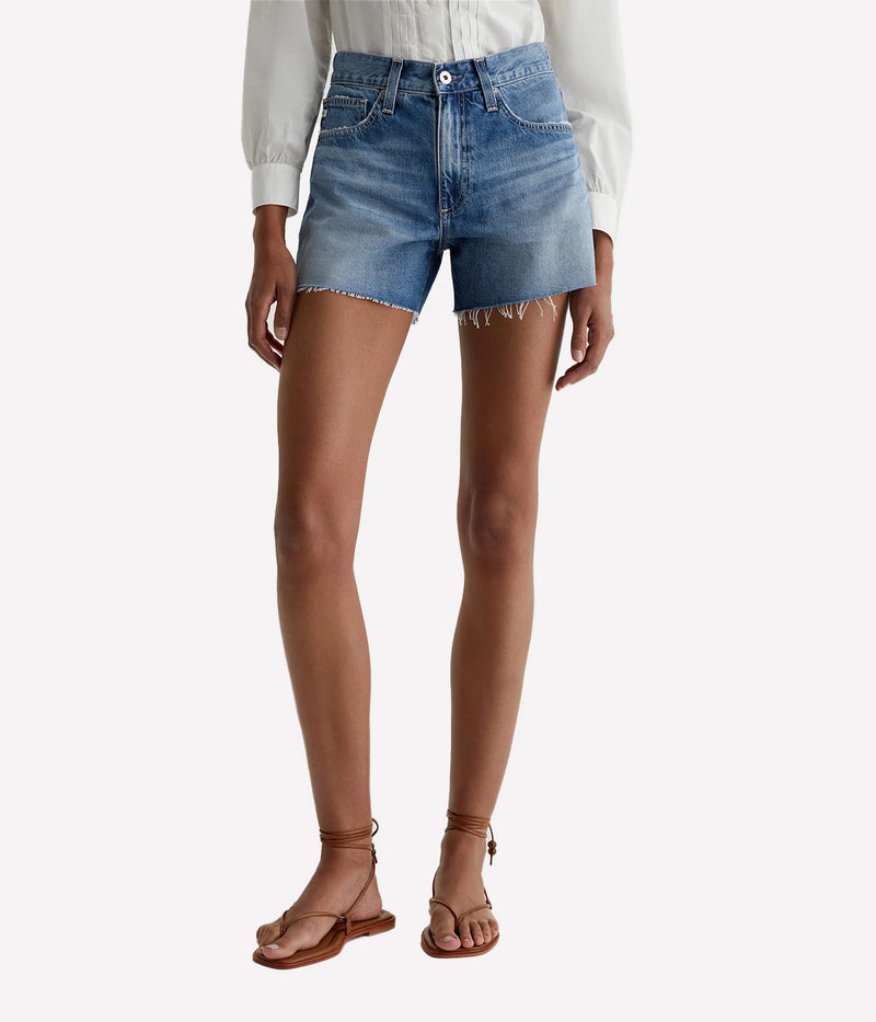 ALT text: High-rise relaxed denim shorts in faded medium blue with raw hems and five-pocket styling.