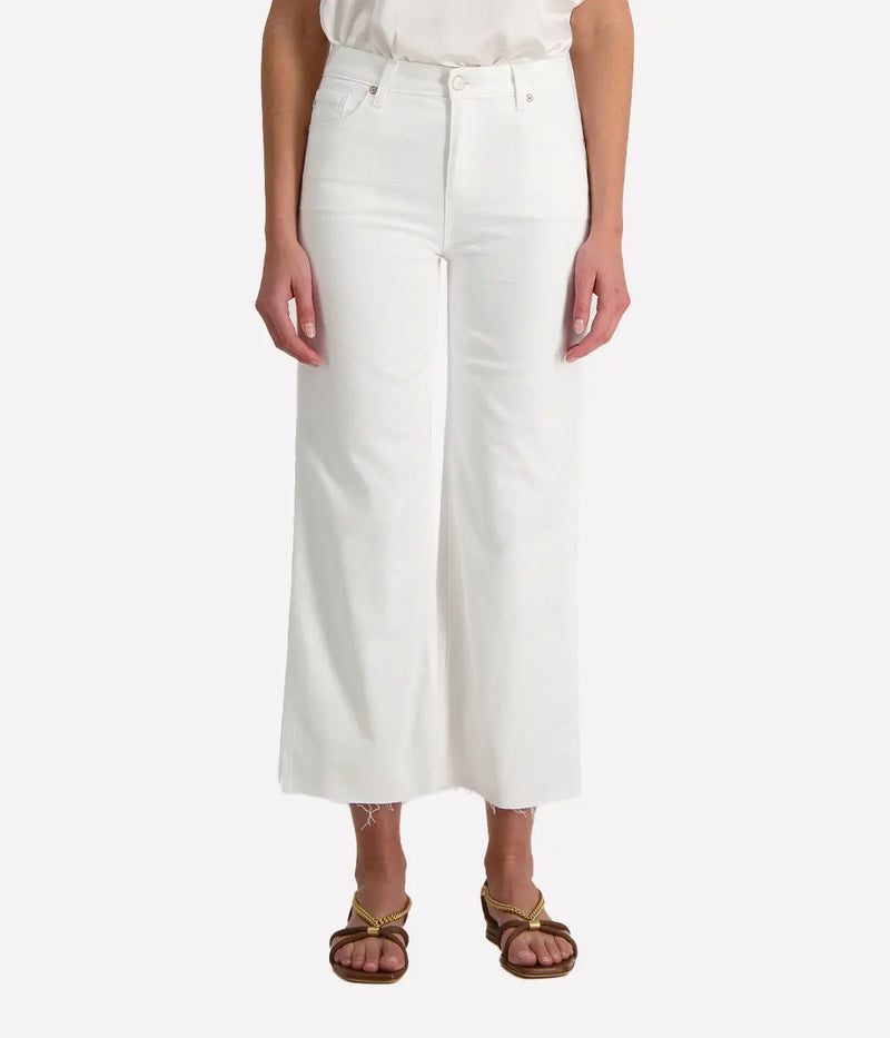 A person standing straight facing forward, wearing wide leg crop jeans in white, with no visible footwear.