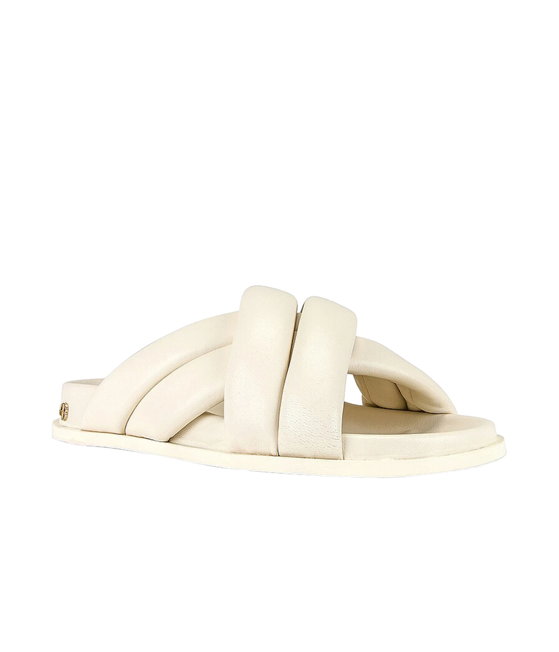 ALT text: Ivory flat sandals with puffy cross-over straps and gold-tone ANINE BING monogram at the heels.