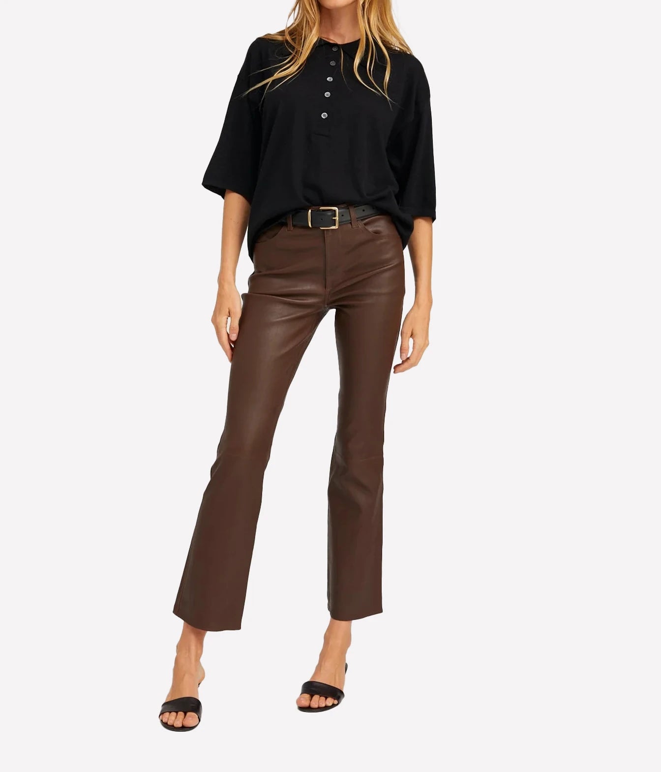 A woman modeling a black short-sleeve button-front top and brown faux-leather cropped flare pants with a black belt, paired with black heeled sandals, against a light gray studio background.