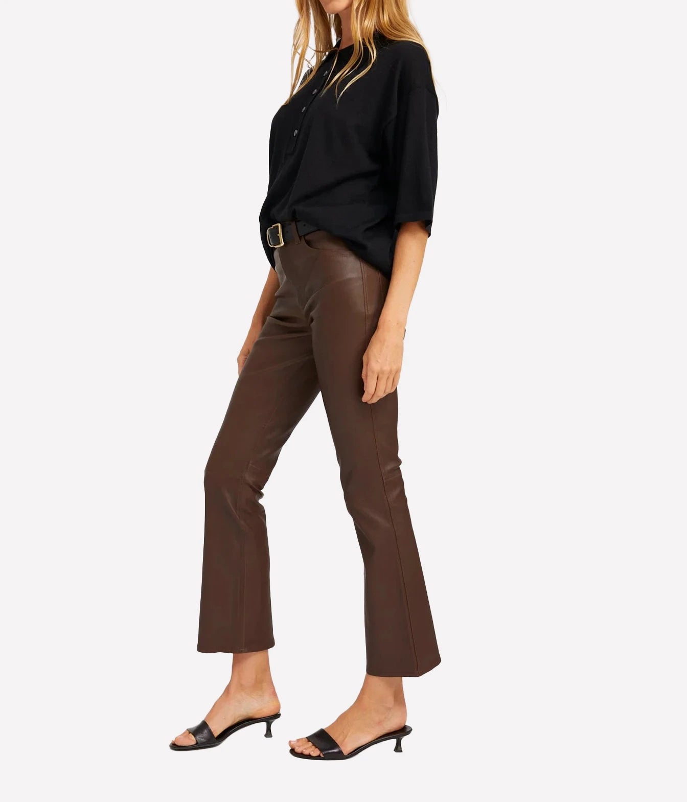 A model wearing brown cropped flare pants with a black button-down shirt and black slide sandals, shown from the waist down against a light gray background.