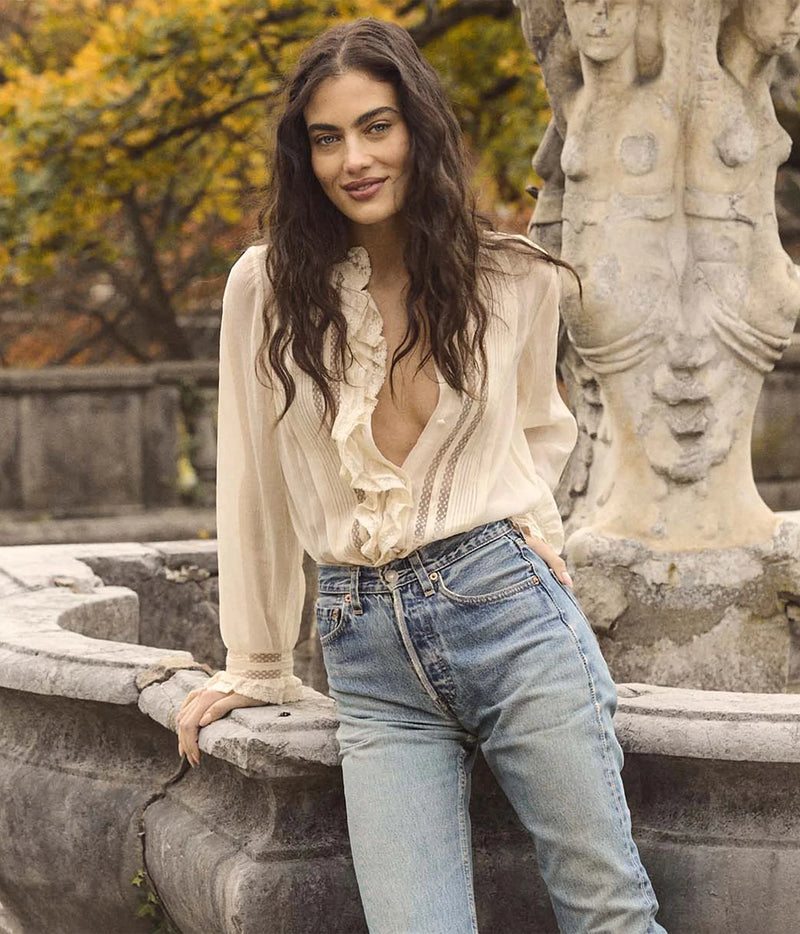 Model wearing the DÔEN Magdeleine Top In Candlelight open at the neck and tucked into light-wash straight-leg jeans