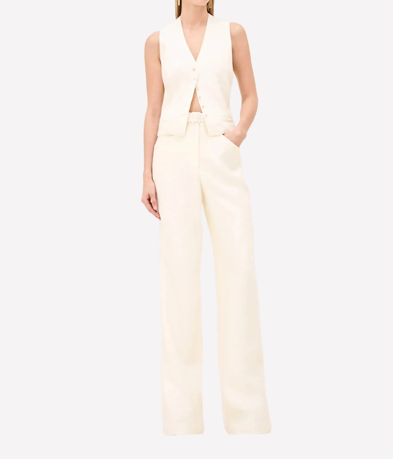 A model wearing a cream-colored sleeveless vest and matching wide-leg trousers, shown against a plain light gray studio background.