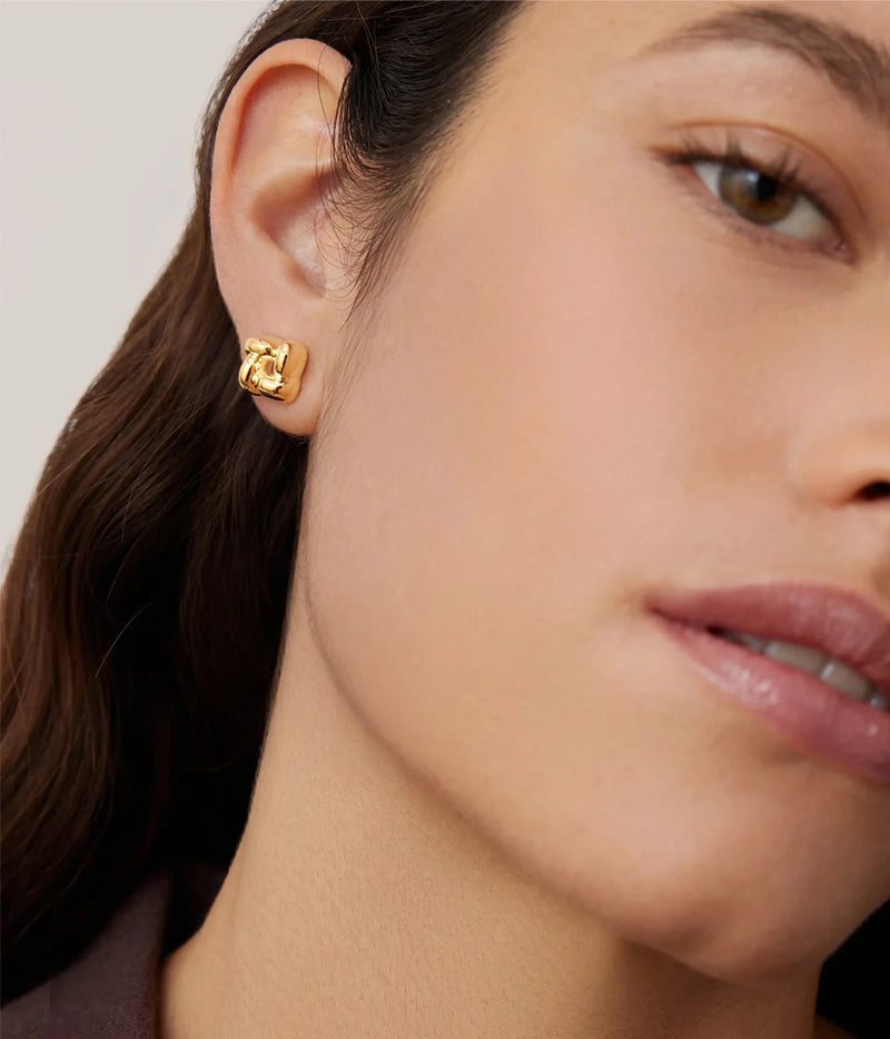 Side profile of a model with dark hair pulled back wearing the Jenny Bird Mini Woven Square Earrings in Gold with a brown top