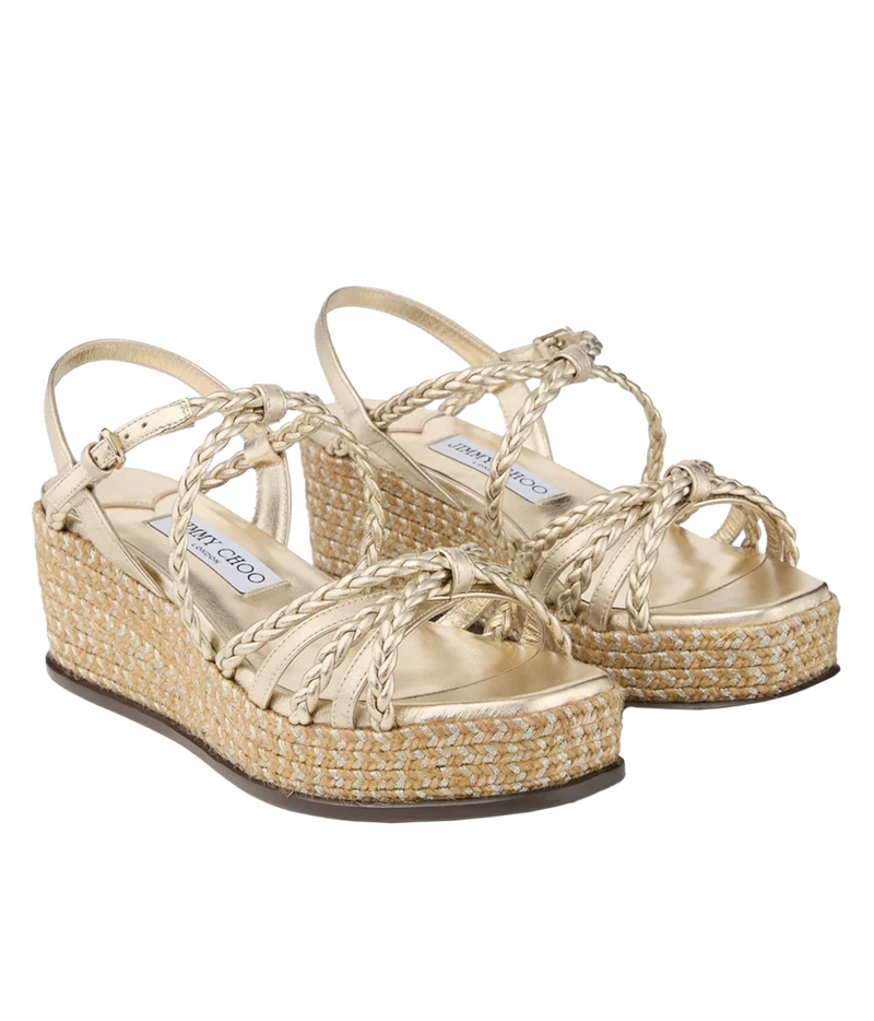 A pair of gold platform wedge sandals with braided straps and woven jute espadrille wedges, shown on a plain white background.