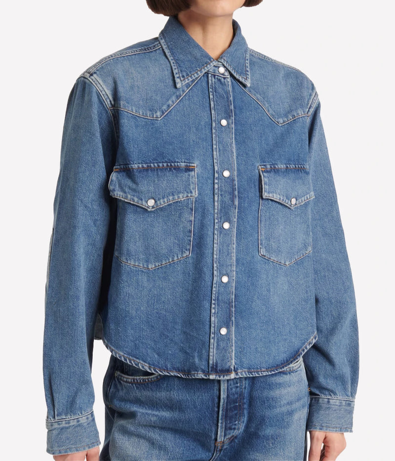 Front view of a model wearing the Citizens Of Humanity Cropped Western Shirt in Chaya snapped closed over mid-wash jeans, showing the cropped length and curved hem