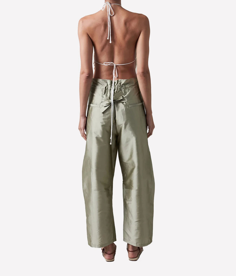 A model shown from the back wearing a light sage green halter top with a tie-back and matching wide-leg pants, set against a plain light gray background.