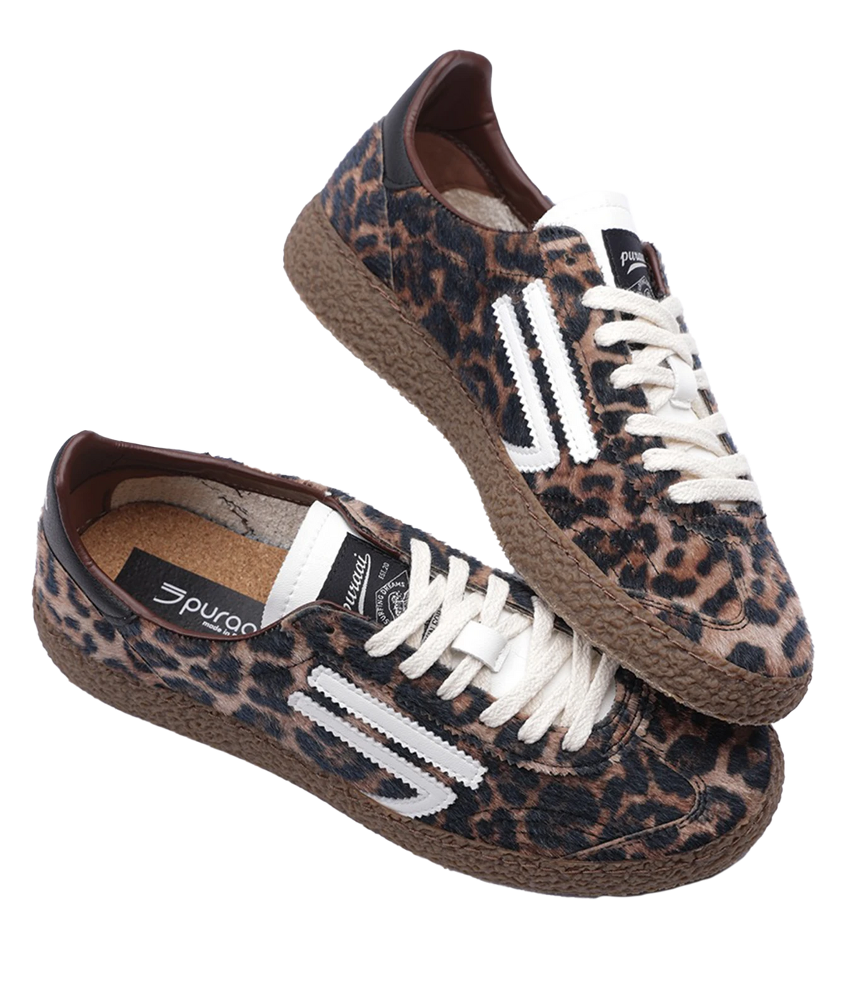A pair of Puraai low-top sneakers featuring a brown and black leopard print canvas upper, white laces, and white side stripes, set against a plain white background.