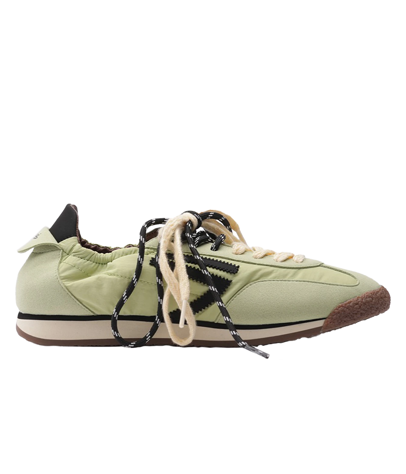 A light green low-top sneaker with black and white patterned laces, beige laces, a cream midsole, and a brown gum outsole, shown from a side profile on a white background.