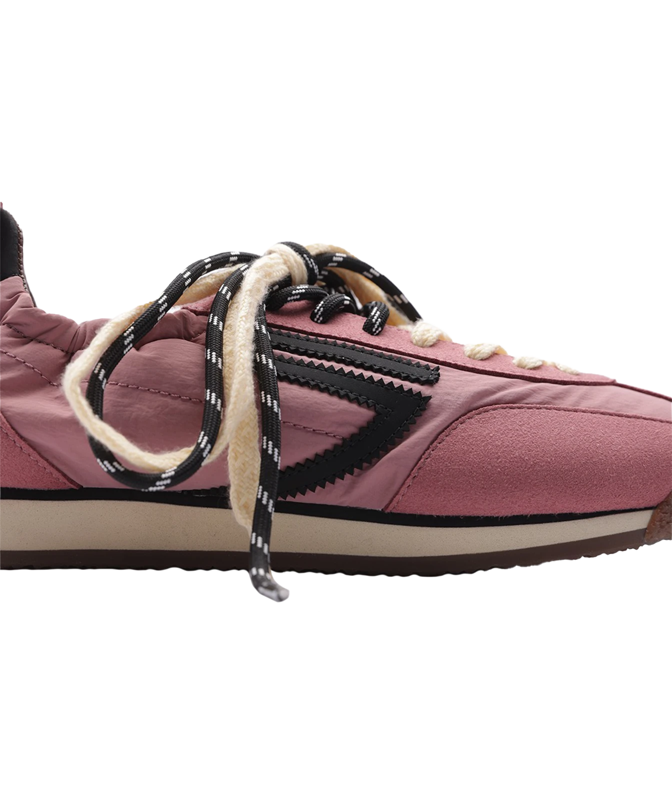 A close-up side view of a pink suede sneaker with black and white patterned laces, a black chevron side stripe, and a beige midsole on a white background.