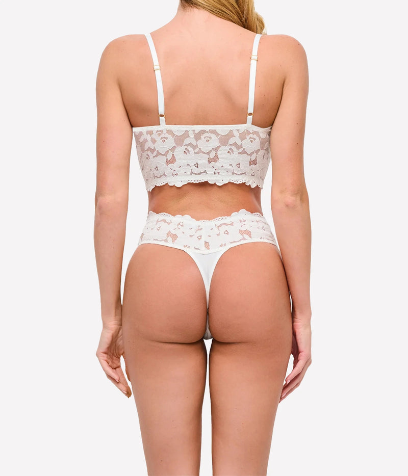 Back view of a model wearing the Cosabella Romanza Longline Bralette in Moon Ivory with a matching ivory lace thong, showing the thin straps and lace back band