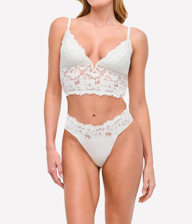Model wearing the Cosabella Romanza Longline Bralette in Moon Ivory with a matching ivory lace thong, arms relaxed at her sides, showing the fitted longline silhouette