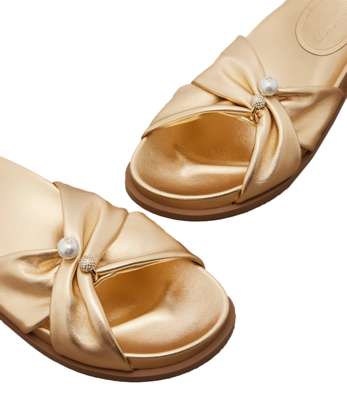 A pair of metallic gold slide sandals with satin bow details and a single white faux-pearl embellishment on the front, shown on a clean white background.