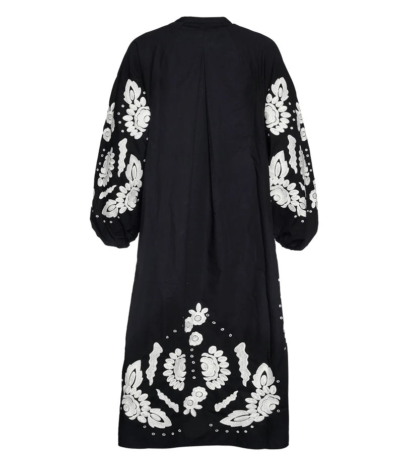 A black long-sleeved maxi dress shown from the back, featuring intricate white floral embroidery concentrated on the sleeves and lower back.