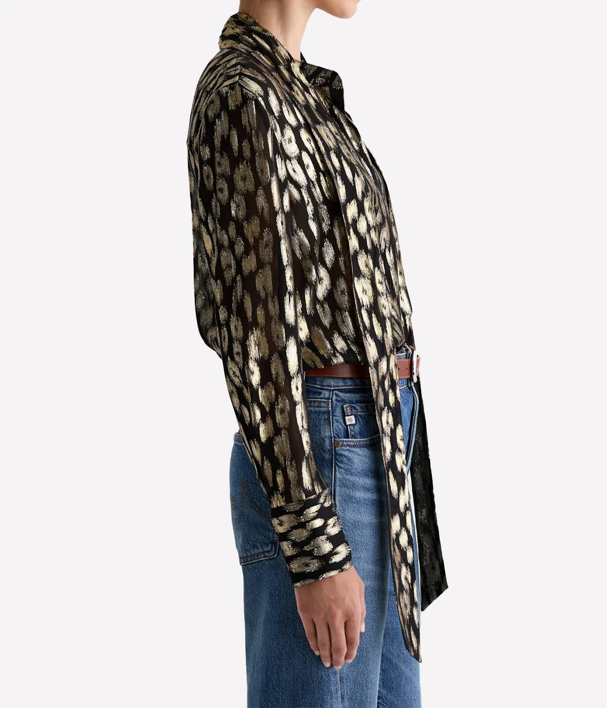 Side profile of a model wearing the AG Lora Tie Neck Shirt in Leopard Lounge tucked into blue jeans, showing the long tie ends falling past the waist