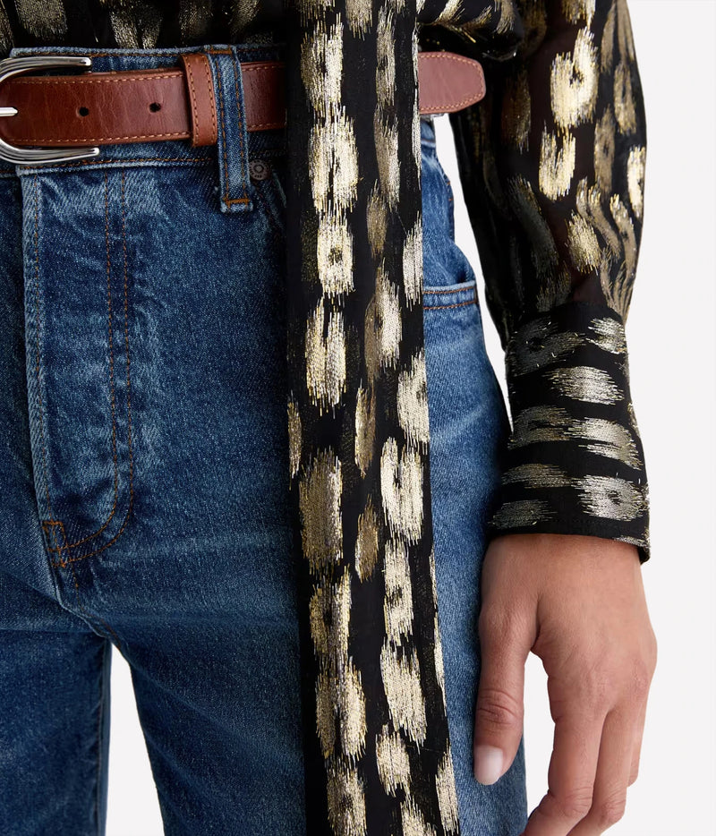 Close-up of the AG Lora Tie Neck Shirt in Leopard Lounge showing the tie end and print detail against blue jeans and a brown leather belt