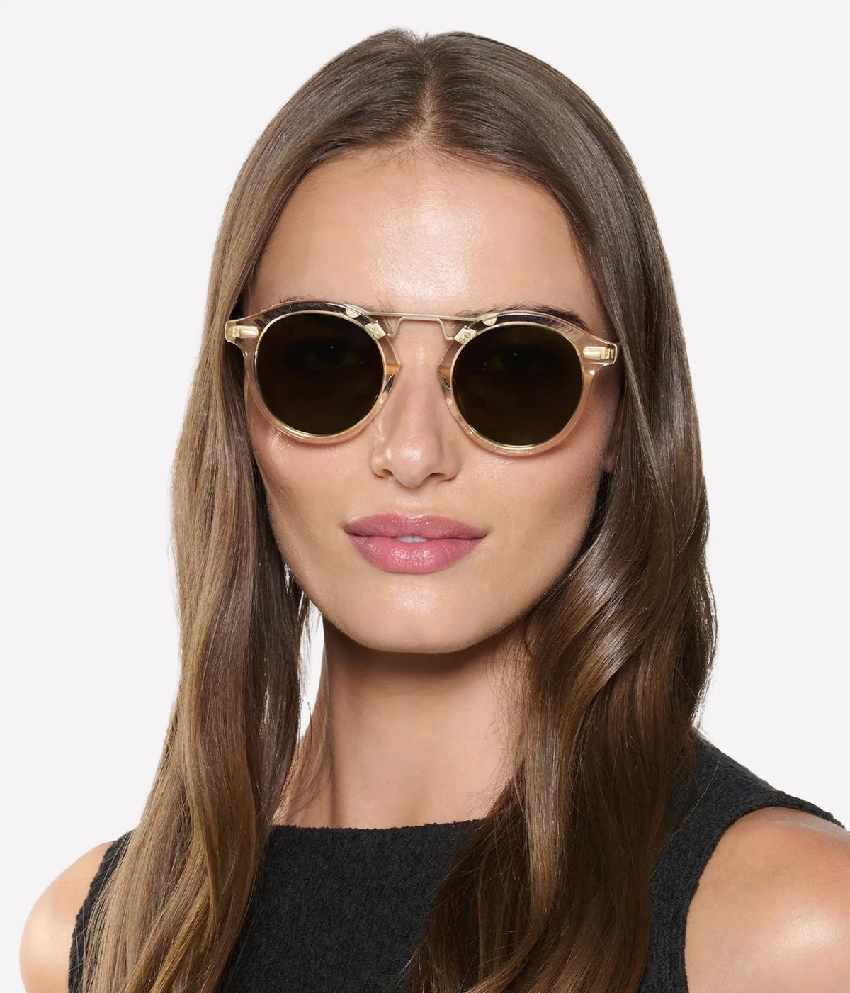Model with long brown hair wearing the KREWE STL II Sunglasses in 12K Haze Iberia with a black sleeveless top, front view