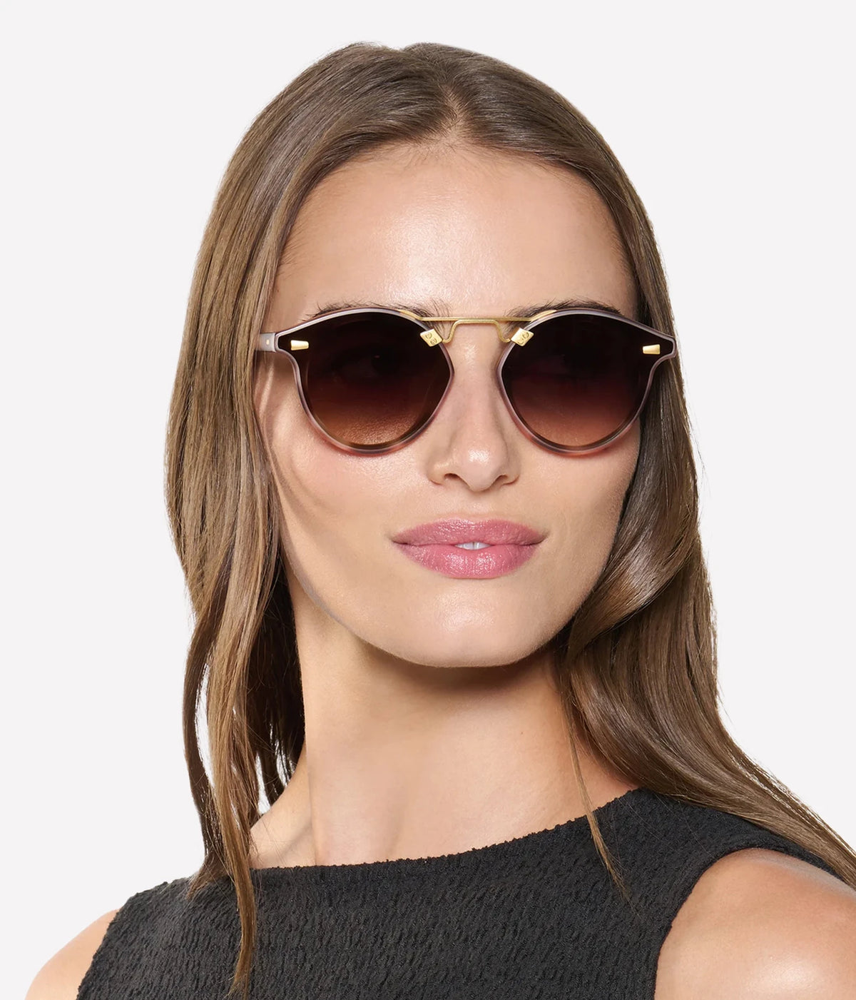 Model with long brown hair wearing the KREWE STL Nylon Sunglasses in 18K Matte Blush Tortoise with a black sleeveless top, front view