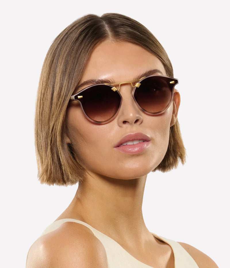 Three-quarter view of a model with a short bob wearing the KREWE STL Nylon Sunglasses in 18K Matte Blush Tortoise with a cream top