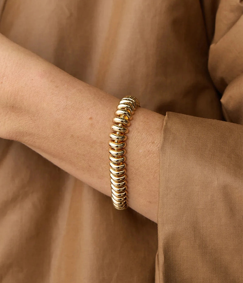 Model wearing the Jenny Bird Sofia Bracelet in Gold on her wrist with a camel long-sleeve top