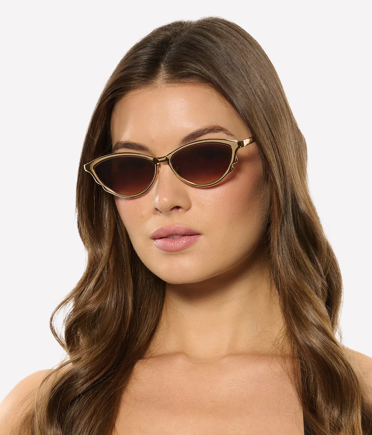 Model with long wavy brown hair wearing the KREWE Solange Sunglasses in 18K Chroma Champagne, front view