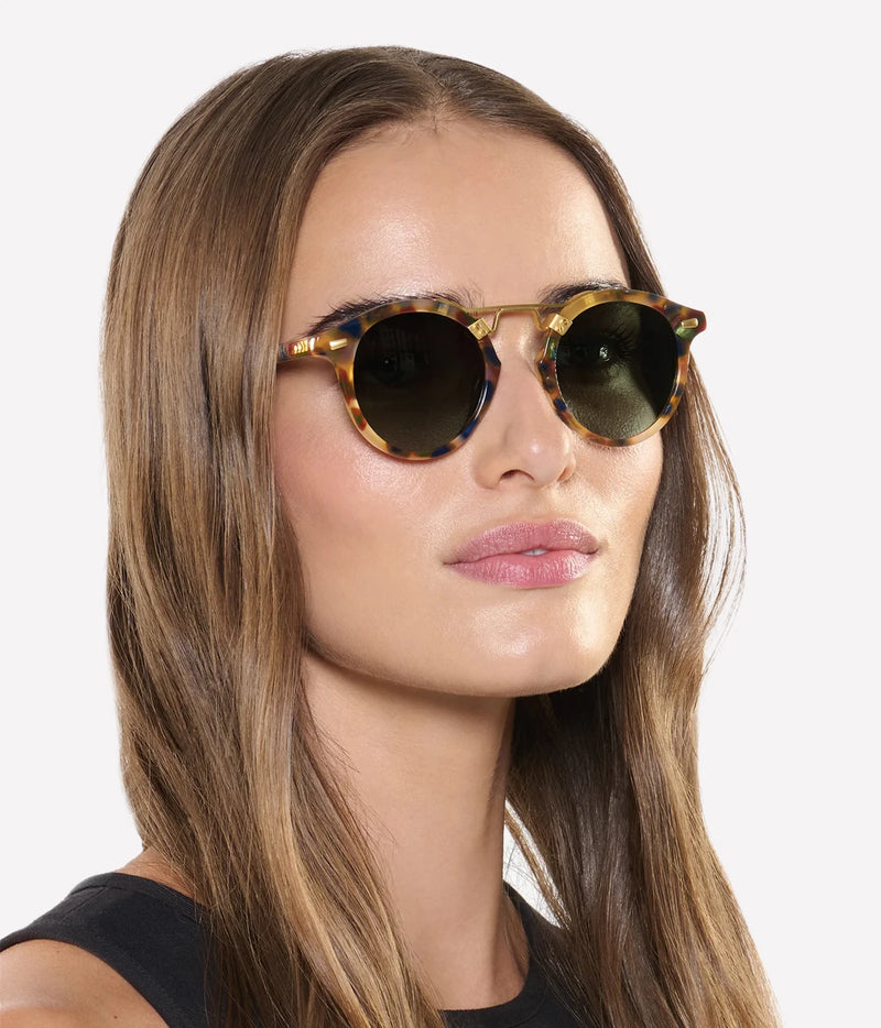 Three-quarter view of a model with long brown hair wearing the KREWE St. Louis Sunglasses in 18K Tuscan Tortoise with a black top
