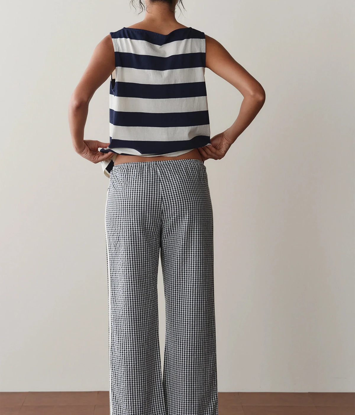 Model wearing navy gingham check pants with a striped tank top, front view showing the elastic waist and contrast side stripe.