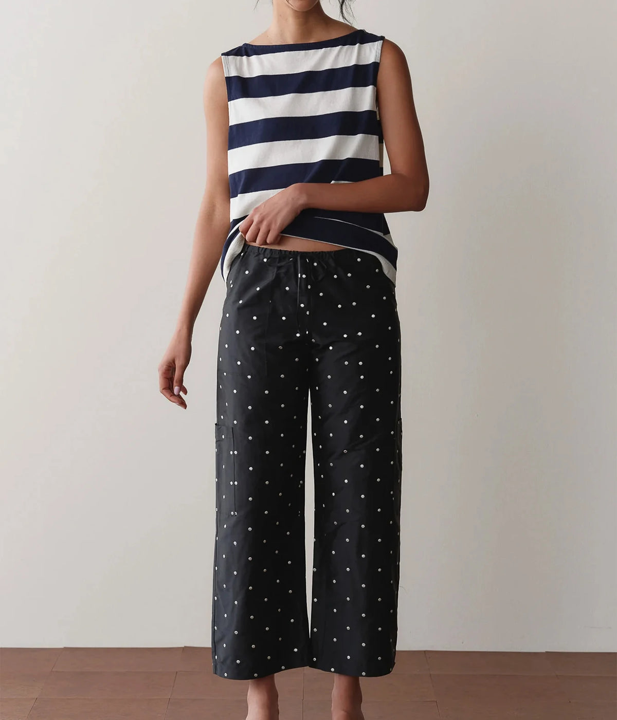 Model wearing black polka dot cargo pants with a striped tank top, standing front-on to show the relaxed straight-leg fit and drawstring waist.
