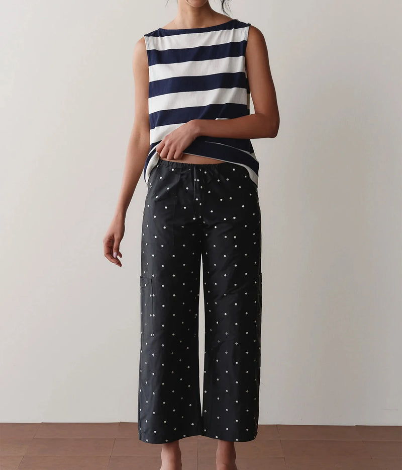 Model wearing black polka dot cargo pants with a striped tank top, standing front-on to show the relaxed straight-leg fit and drawstring waist.