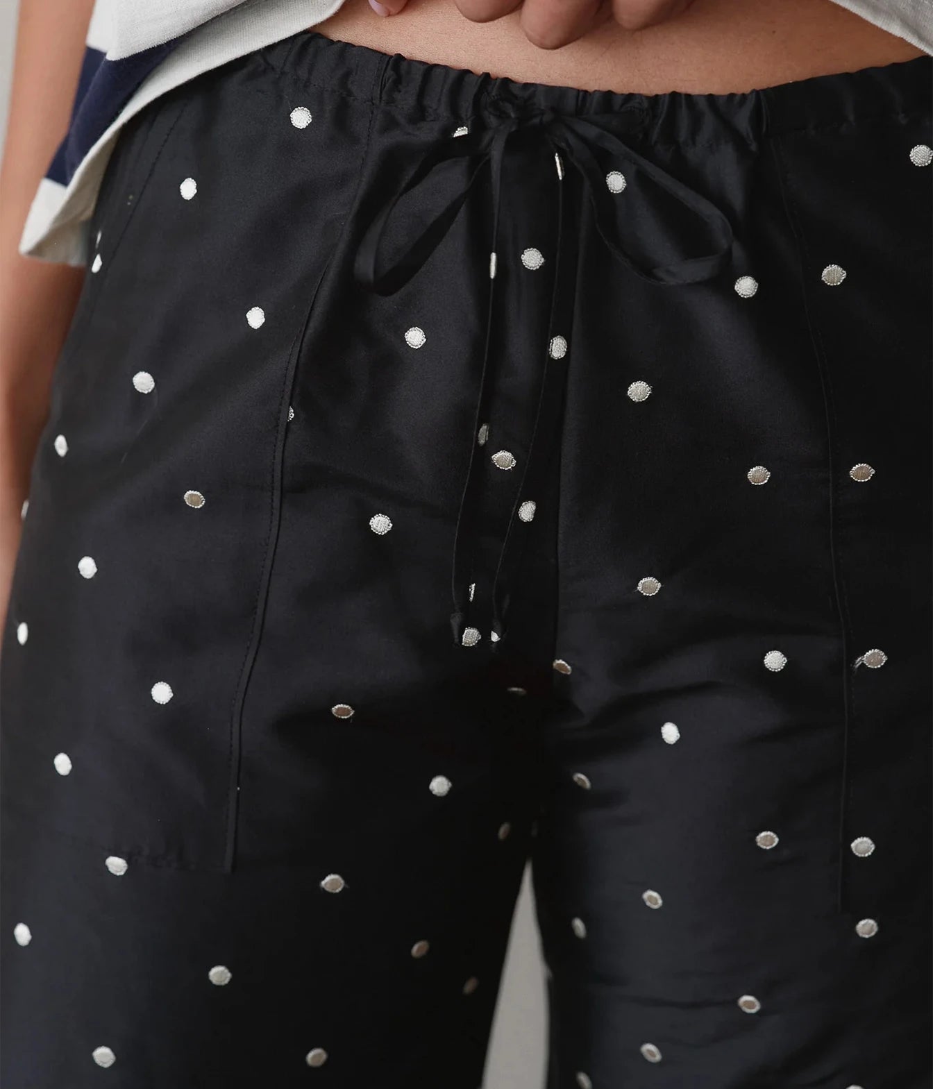 Close-up of black polka dot cargo pants showing the elastic drawstring waist and cargo pocket detail.