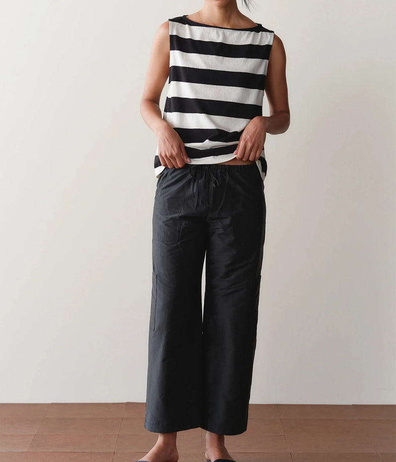Model wearing black cargo pants with a striped tank top, side view showing the side cargo pocket.