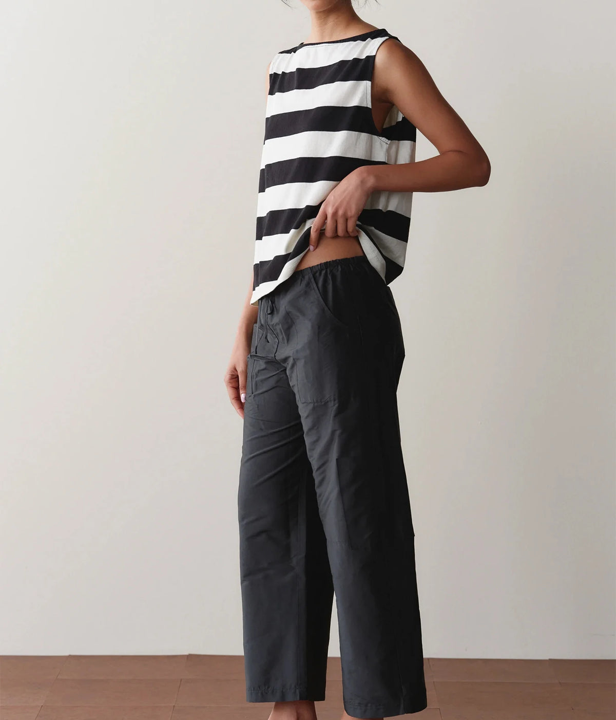 Model wearing black cargo pants, side view against a wall showing the relaxed leg silhouette.