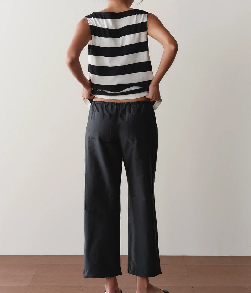 Model wearing black cargo pants with a striped tank top, side profile view showing the straight-leg fit.
