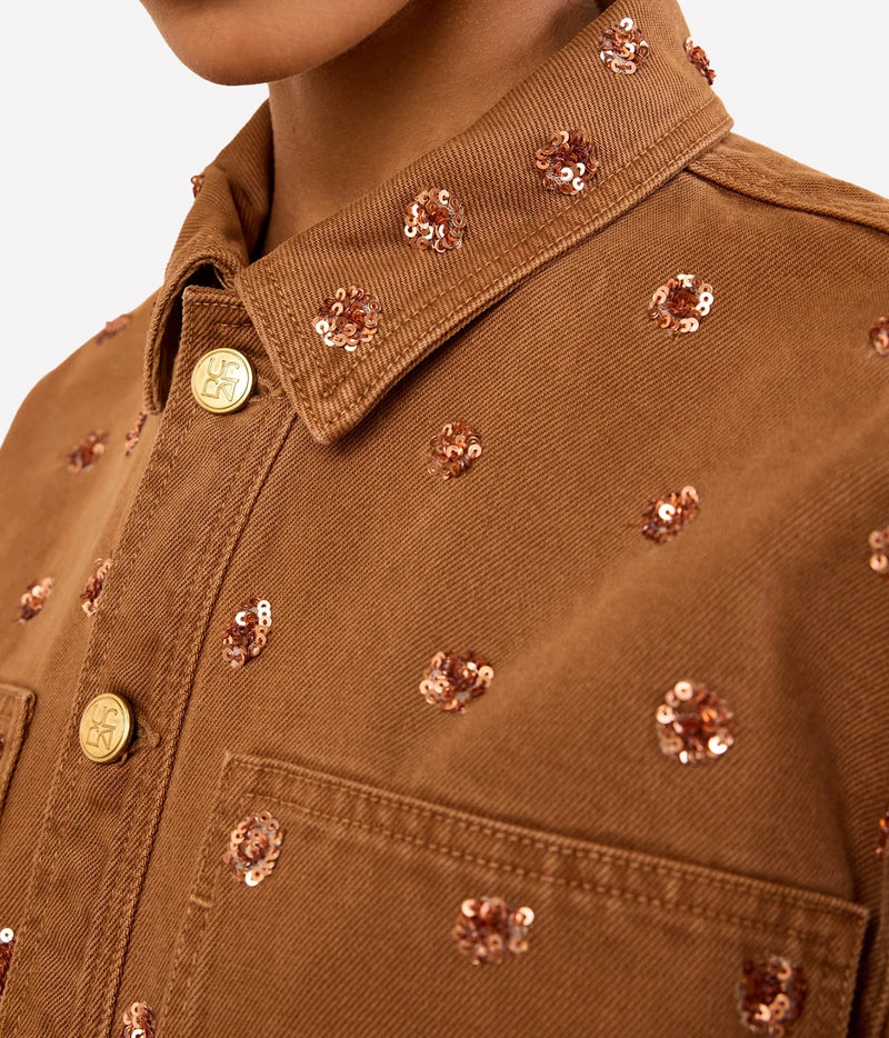 Close-up of Ulla Johnson The Bobbi Embellished Denim Jacket in Umber with floral embellishments and gold-tone buttons