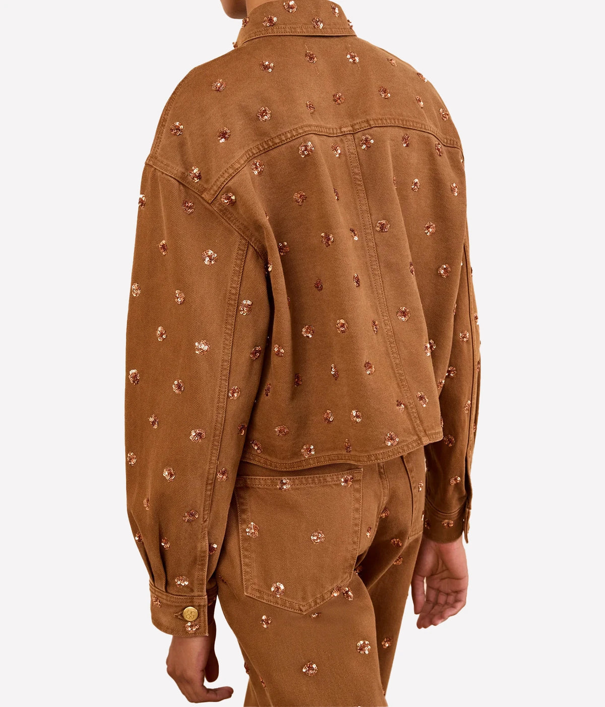 Model wearing Ulla Johnson The Bobbi Embellished Denim Jacket in Umber, back view