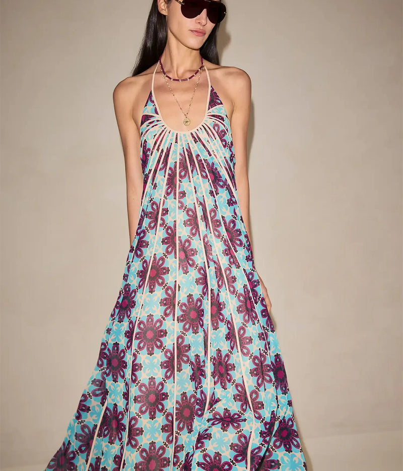 Front view of a model wearing the Alexis Azurea Dress In Jardin Sable with black sunglasses, showing the plunging halter neckline, gathered bodice and fluid midi skirt