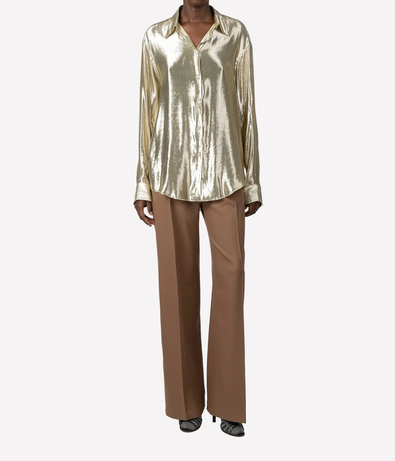 A model wearing a metallic gold satin long-sleeve button-up shirt and brown wide-leg trousers, shown from the neck down against a light gray background.