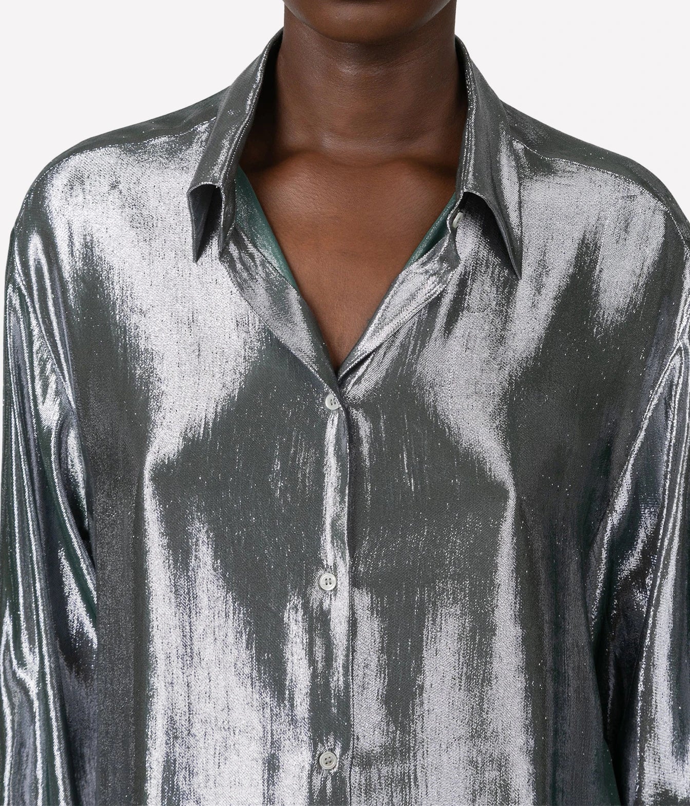 A close-up of a metallic silver button-down shirt with a textured, crinkled finish, worn by a model against a plain white background.