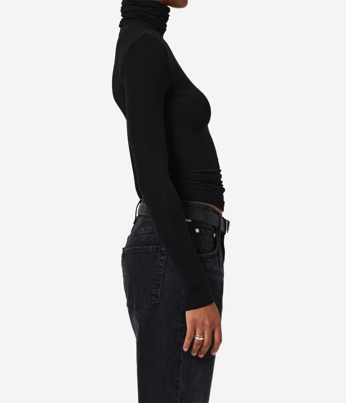 Person wearing a black turtleneck and dark jeans on a white background