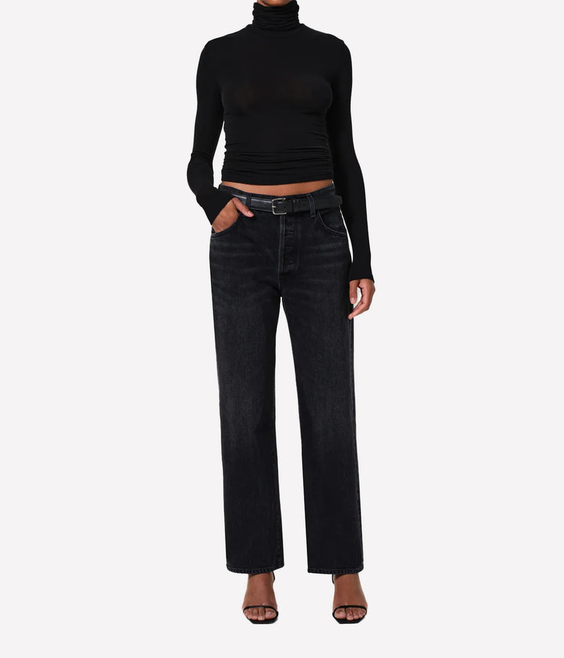 Person wearing a black turtleneck and dark jeans on a white background