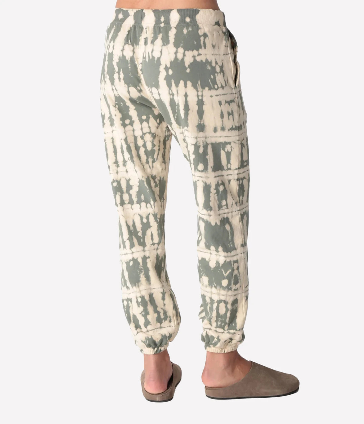 Back view of a model wearing the Electric Rose Classic Horizon Jogger in Moss Ivory, showing the relaxed fit through the seat and gathered ankle cuffs, with taupe suede clogs