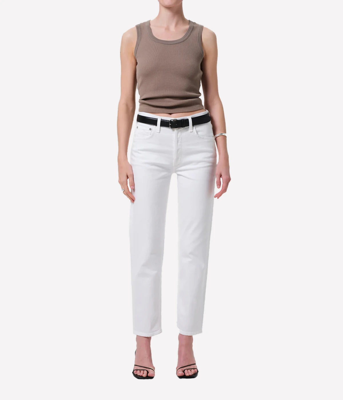 Person wearing a brown tank top and white pants on a white background