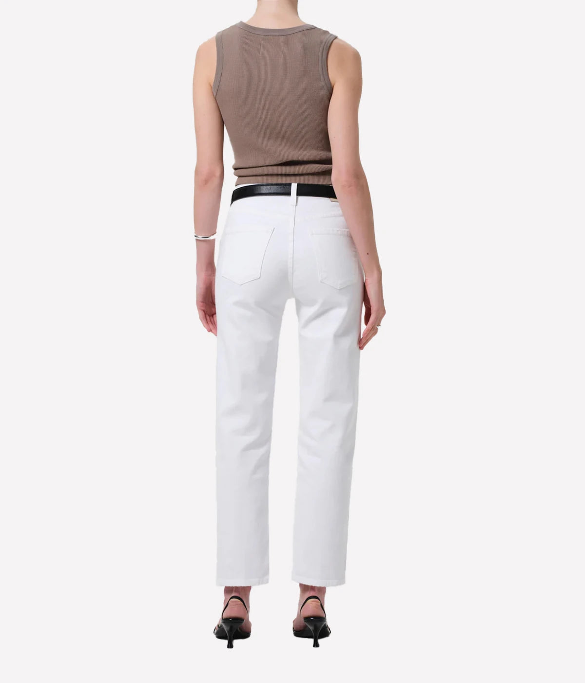Person wearing a sleeveless brown top and white pants on a white background