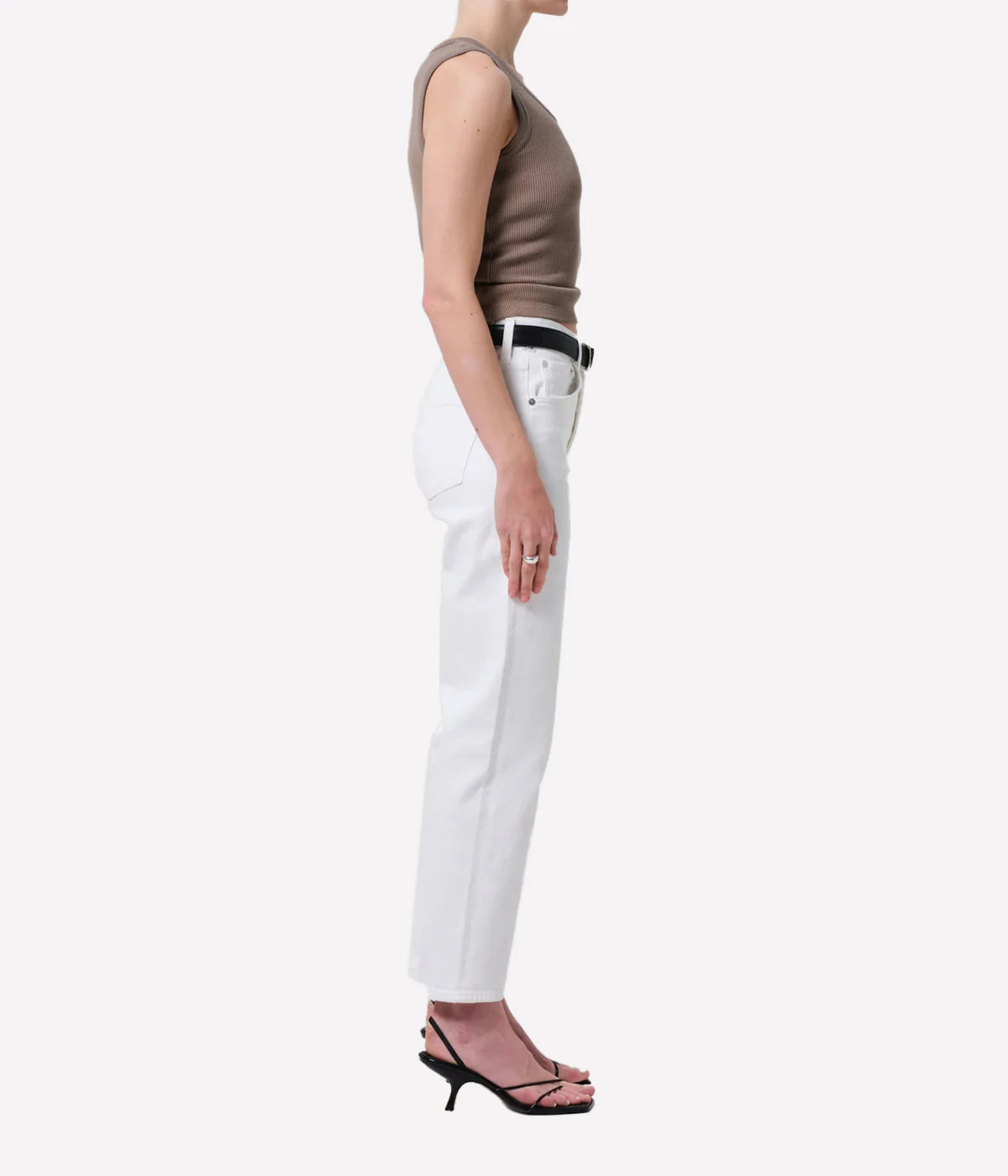 Person wearing a sleeveless brown top and white pants on a white background