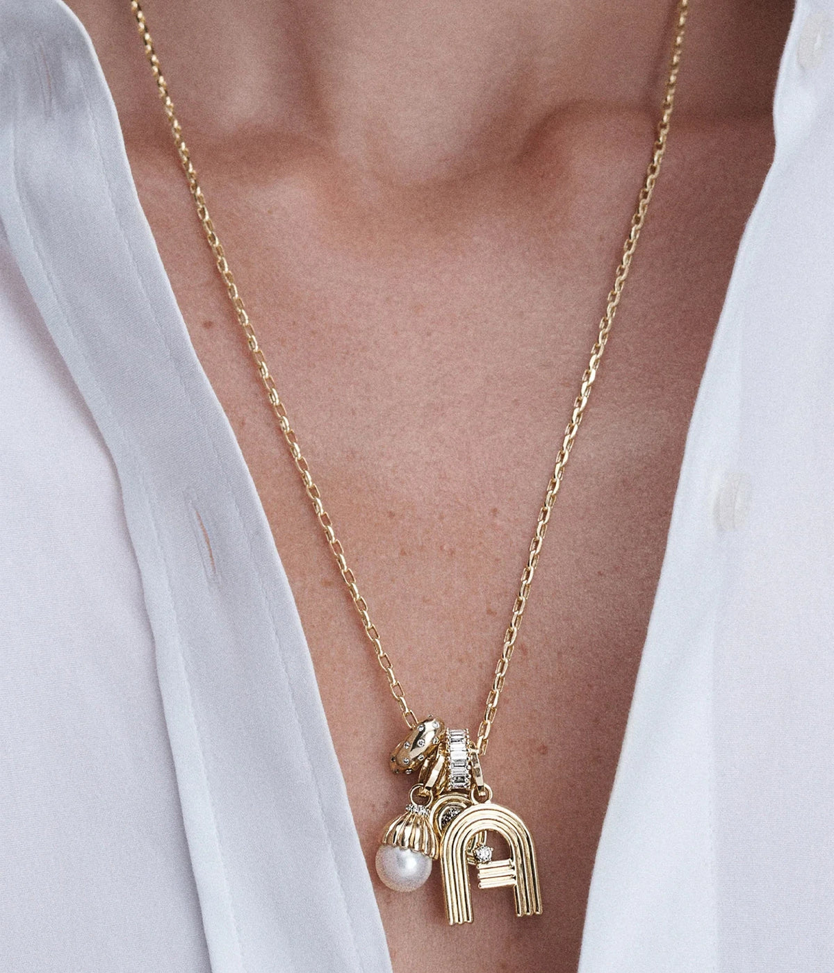 Model in an open white shirt wearing the Adina Reyter Diamond Polka Dot Big Bead in 14K Yellow Gold with a cluster of gold charms on a long chain