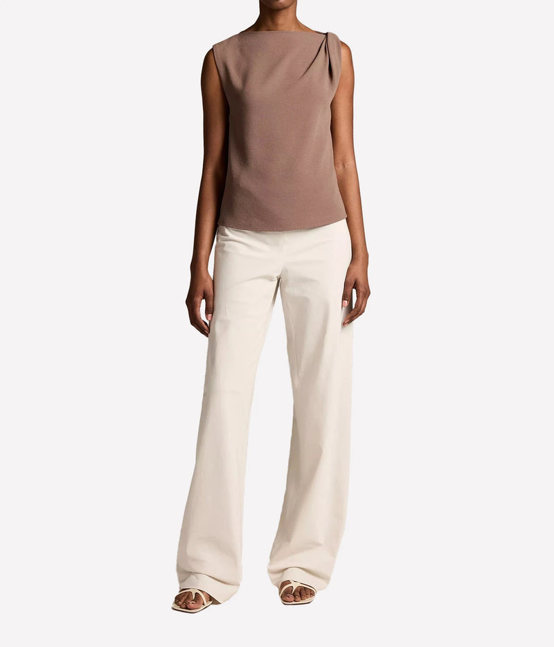 A model wearing a sleeveless draped top in taupe and wide-leg cream trousers