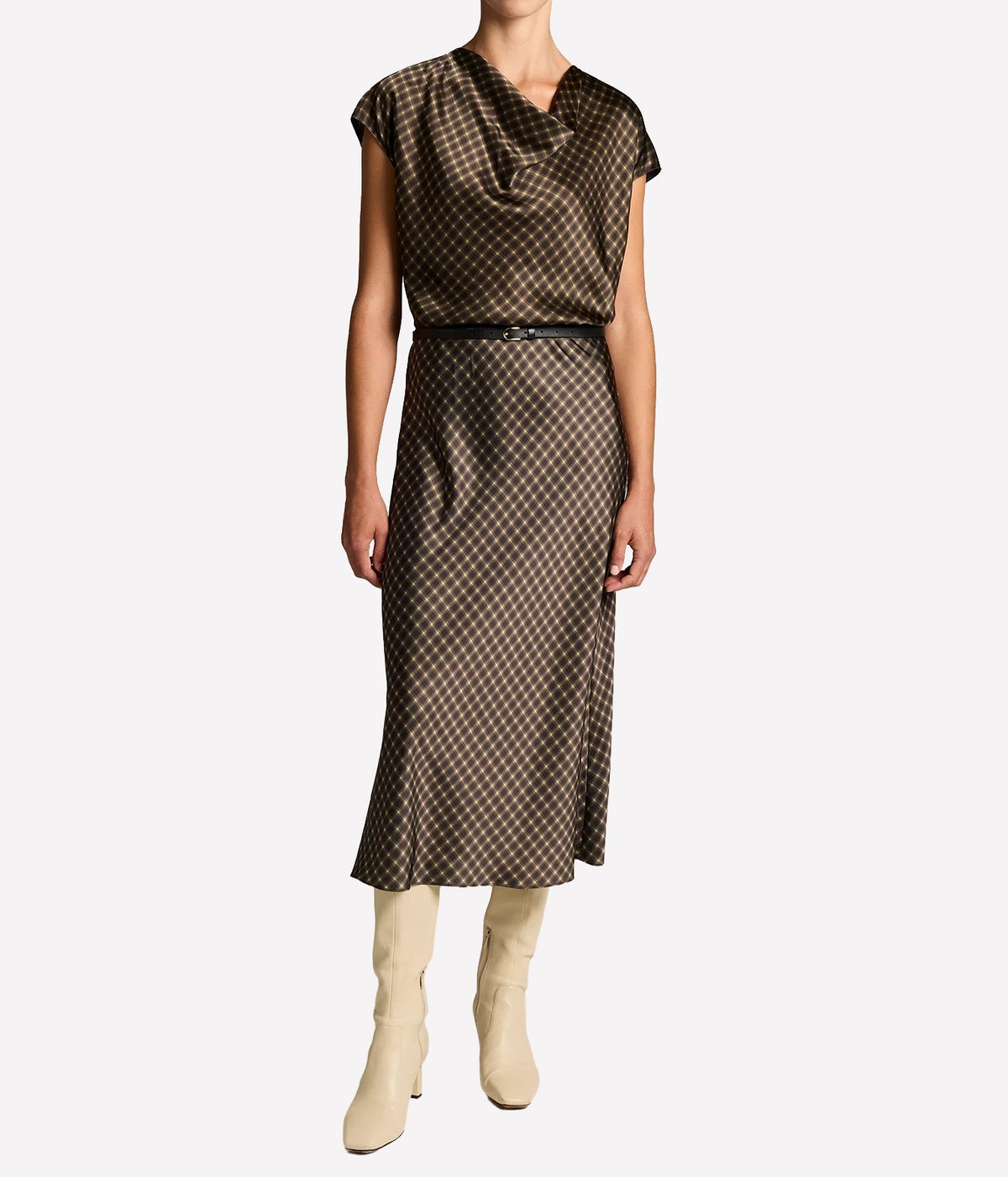 Full-length front view of a model wearing the Vince Ombre Plaid Blouse In Black Camel with the matching plaid midi skirt, a thin black belt and cream knee-high boots
