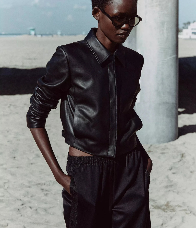 A model wearing a black leather jacket and matching black pants