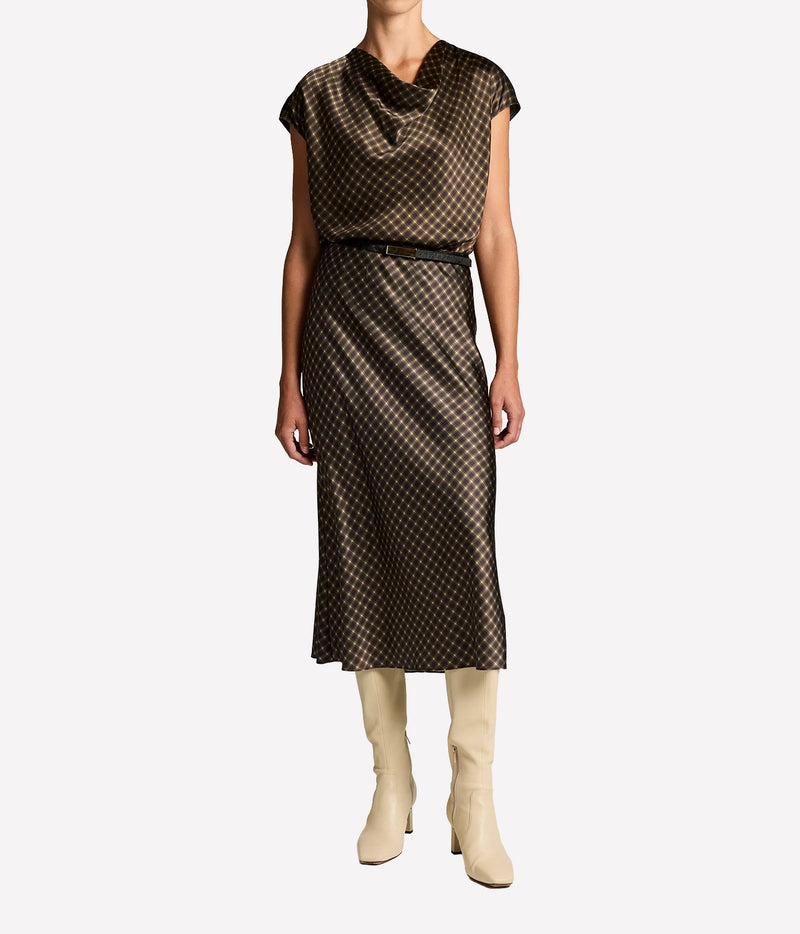 Full-length front view of a model wearing the Vince Ombre Plaid Skirt In Black Camel with the matching cowl neck blouse, a thin black belt and cream knee-high boots